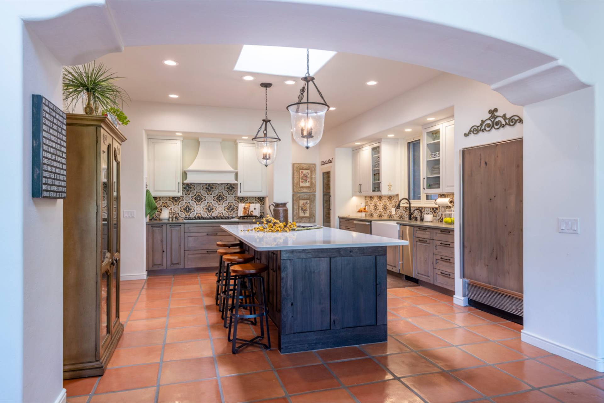 Second Diamond kitchen view with weathered-oak cabinetry, a blue-stained island, patterned tile backsplash, and terracotta floor