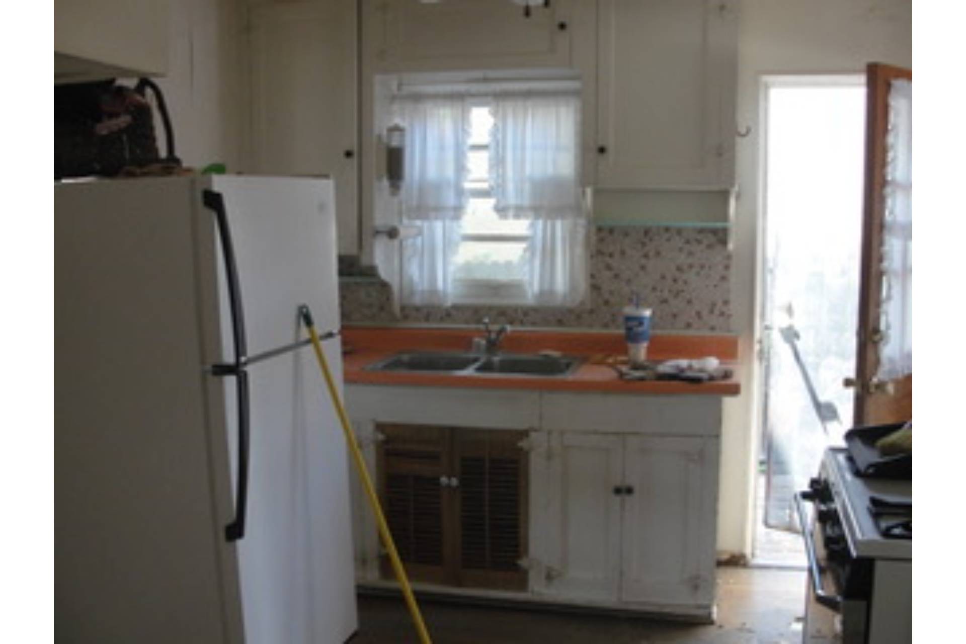 Distefano kitchen before remodel — Catalina Foothills, dated galley with dark cabinet under a laminate-top sink and separate refrigerator wall