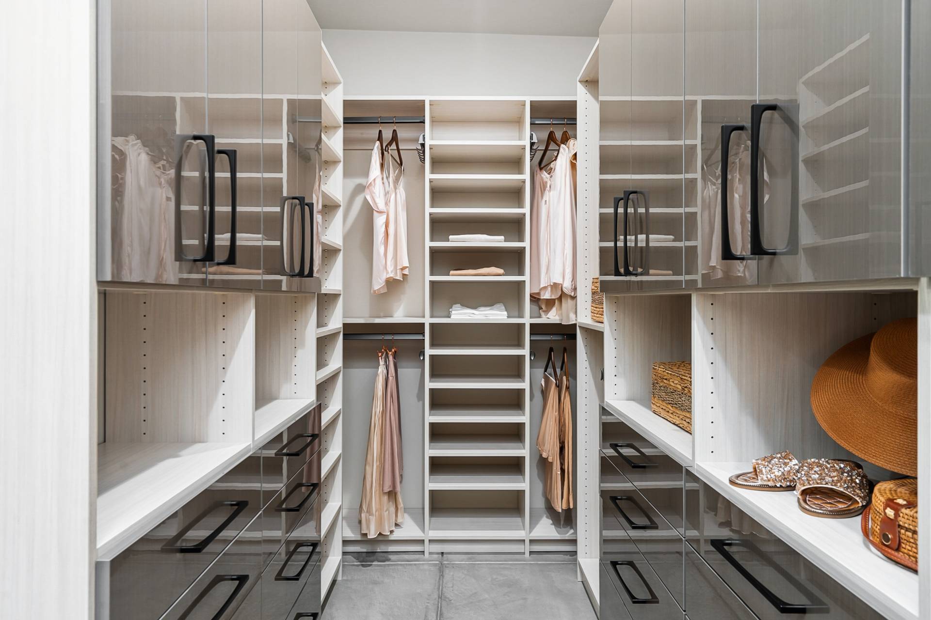 Garden Drive walk-in closet fitted wall-to-wall in glossy two-tone cabinetry with black hardware and open shelving