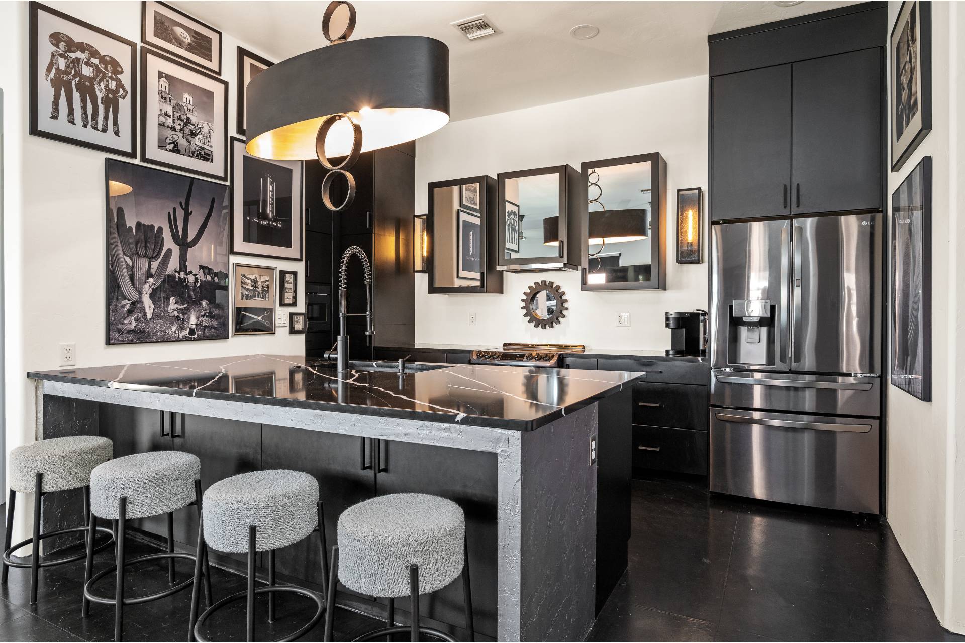 All-black Gassel kitchen with matte cabinetry, a book-matched black marble waterfall island, gray boucle stools, and a salon-style black-and-white photography wall