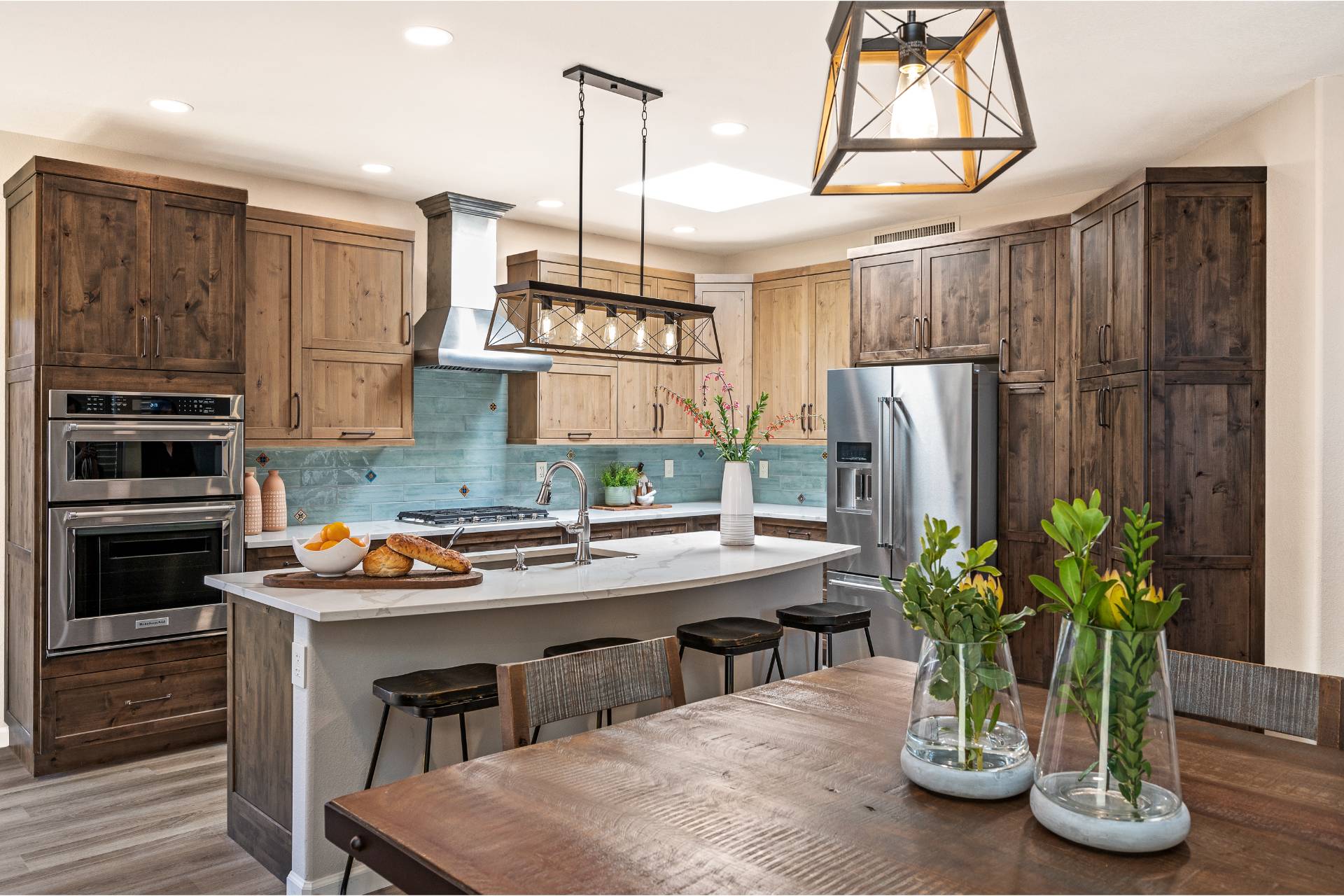 Hydukovich kitchen in two-tone knotty alder with a weathered-teal tile backsplash, marble-look quartz counters, and a geometric iron pendant