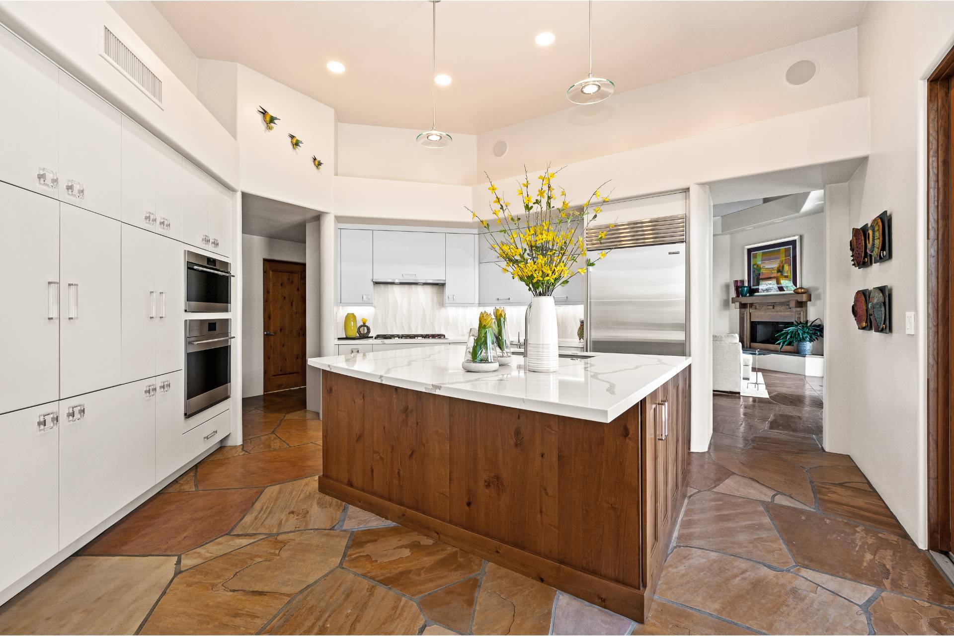 Wide view of the Ponder kitchen opening to the adjacent living room, with dual wall ovens and a stainless built-in refrigerator