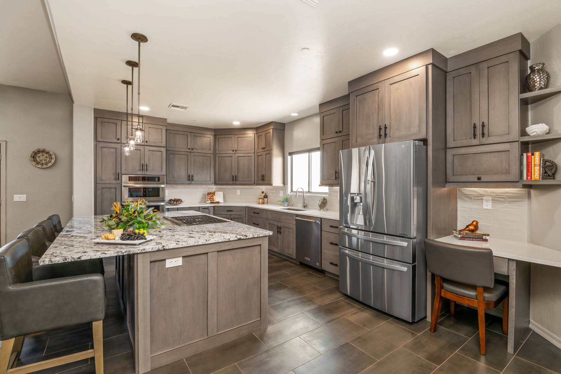 Tobey gray-stained shaker kitchen with a speckled granite peninsula, an integrated desk nook, and stainless appliances